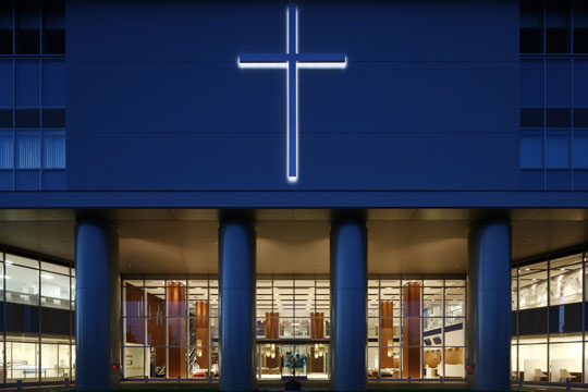 エントランス上部の十字架は、地域医療をを見守る病院のアイデンティティとしてライトアップしている