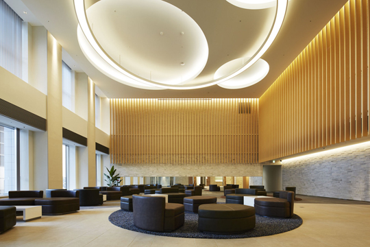 1階エントランスロビー　木目調ルーバーと間接照明、特注円形吊照明など、吟味された素材が演出する寛ぎの空間　©Forward Stroke inc.