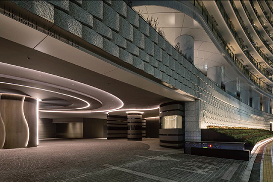 特徴ある石張りの低層外壁の奥にあるコーチエントランス　©川澄・小林研二写真事務所